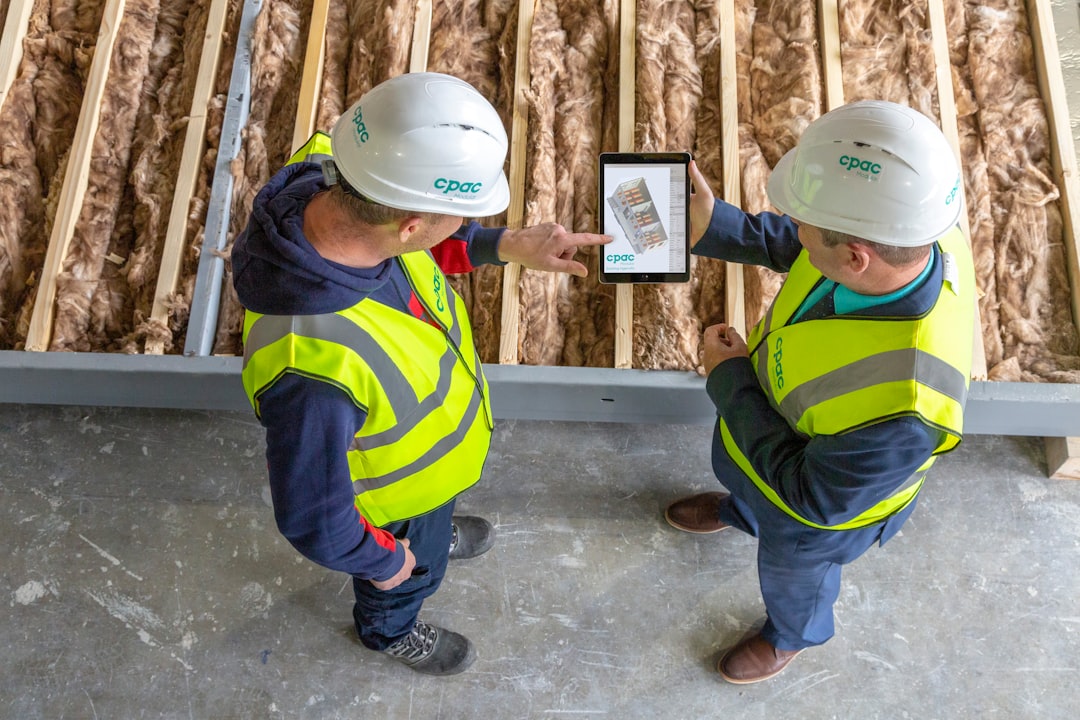Two construction workers review plans on a tablet.