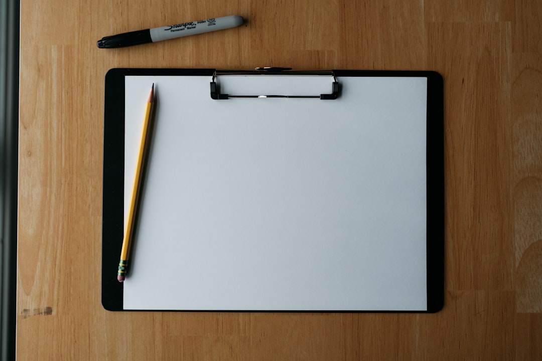 Clipboard, pencil, and pen on a wooden surface