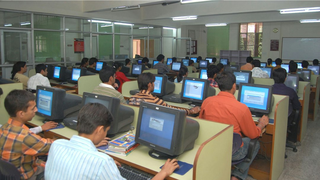 A group of people working at computers in a brightly lit university workspace